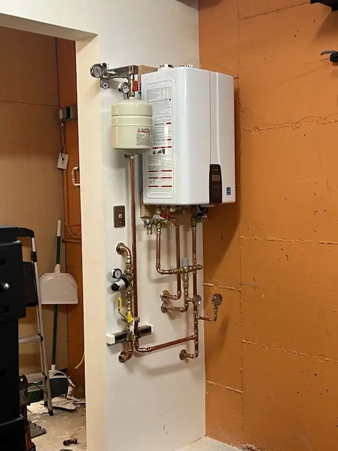 Plumbing technician inspecting water heater connections in Petoskey